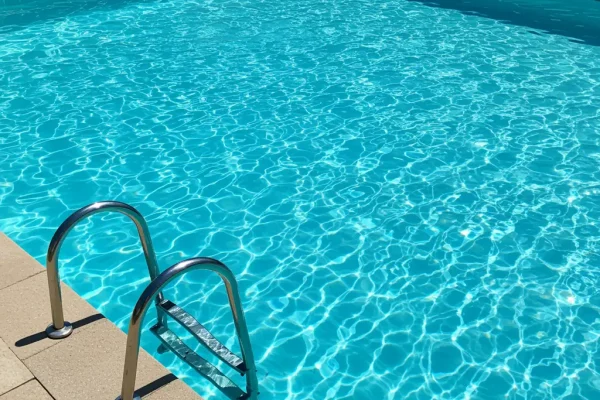 Piscina residencial moderna com água cristalina em área externa, equipada com trocador de calor para aquecimento eficiente.