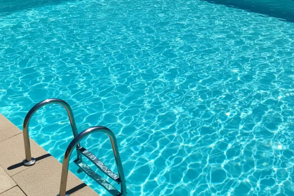 Piscina residencial moderna com água cristalina em área externa, equipada com trocador de calor para aquecimento eficiente.